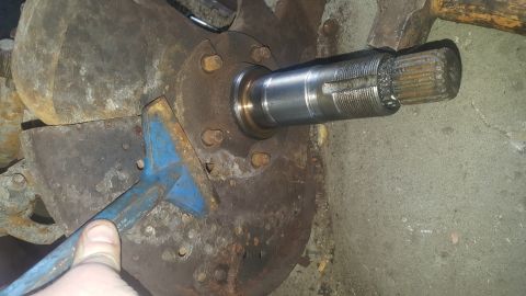 1995 Ford Bronco - A close-up view shows a splined shaft being worked on with a pry bar and hammer, likely part of a vehicle's drivetrain or suspension system…