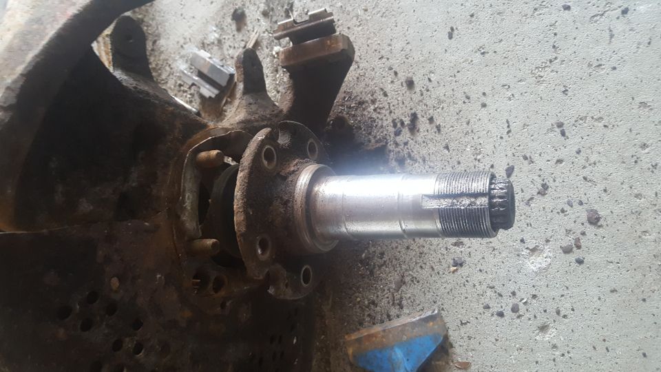 Rusty automotive spindle and hub assembly on concrete