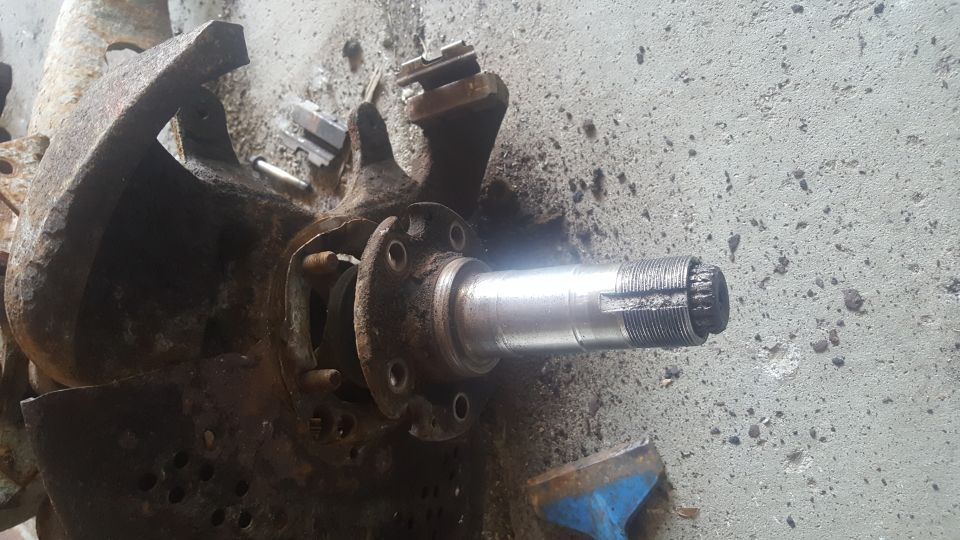 Rusty vehicle spindle assembly with splined end on concrete
