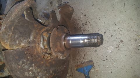 1995 Ford Bronco - A heavily rusted brake rotor and hub assembly with a spindle attached is shown on a concrete surface. A blue and metal tool is visible in t…