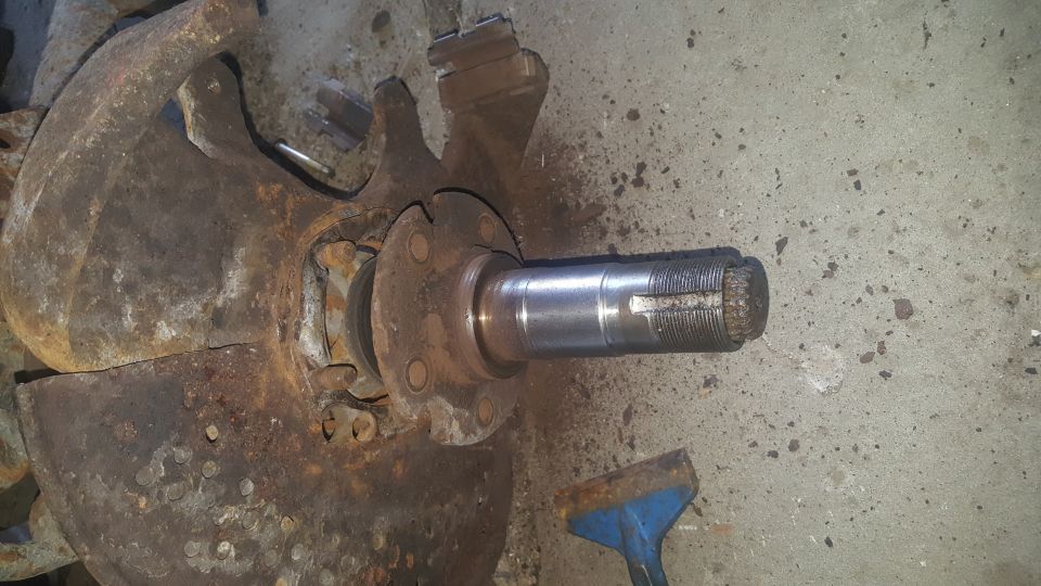Rusted brake rotor and hub assembly with spindle on concrete.