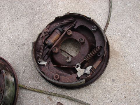 1973 Ford Ranchero - A heavily rusted drum brake assembly, likely from a classic vehicle, sits on a concrete surface. The assembly includes brake shoes, springs…