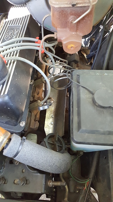 1978 Ford Bronco - A close-up view of a Ford engine bay, featuring the valve cover with "Ford Racing" text, spark plug wires, and various hoses and components.