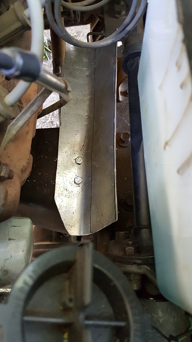 1978 Ford Bronco - A close-up view shows a metal skid plate bolted to the underside of a vehicle's engine bay. The skid plate is silver and shows signs of wea…