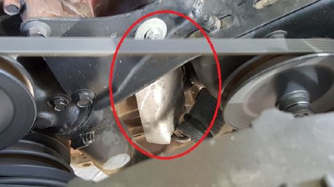 1978 Ford Bronco - A close-up view of the serpentine belt and pulleys on a vehicle's engine. A red circle highlights a metal component near the belt tensioner.