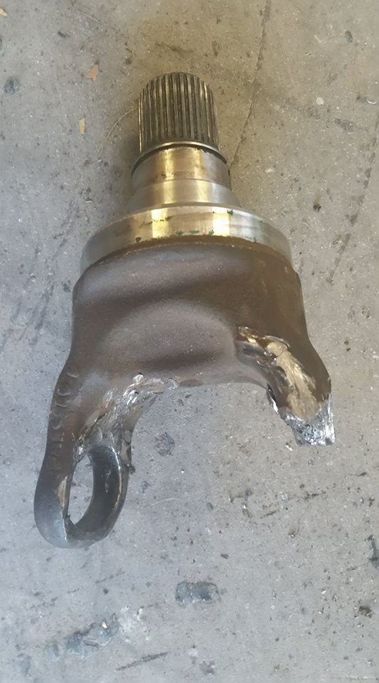 Driveshaft U-joint yoke with splined slip stub showing grease, on concrete