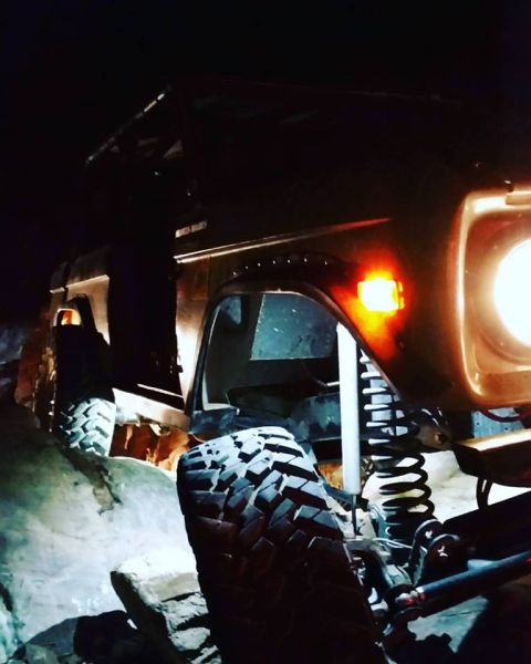 1979 Ford Bronco - A modified off-road vehicle, likely a Ford Bronco, navigates rocky terrain at night. The vehicle's large, aggressive tires and suspension a…
