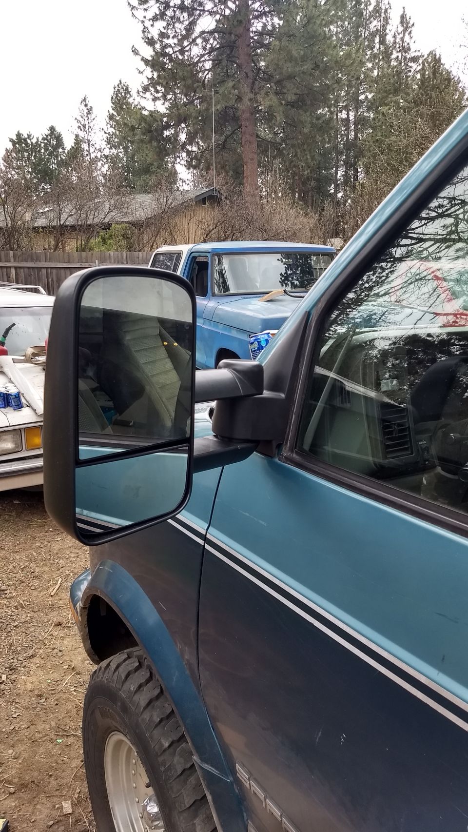 Teal and dark blue van side view with driver's mirror, fender, and tire.