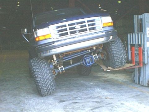 1995 Ford Bronco - Front view of a 1995 Ford Bronco being lifted by a forklift, highlighting its suspension.
