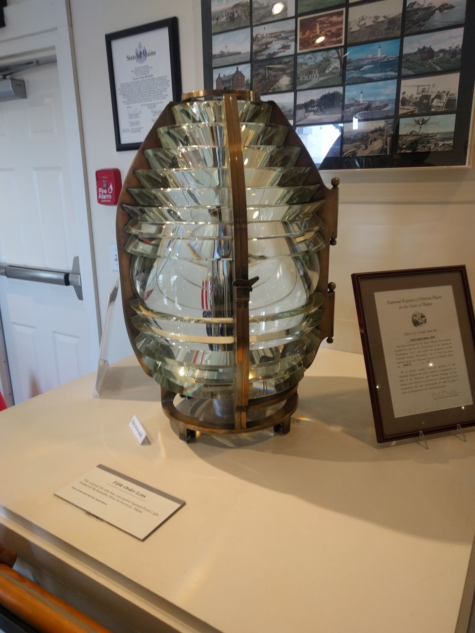 Large Fresnel lens from a lighthouse on display with informational plaques.