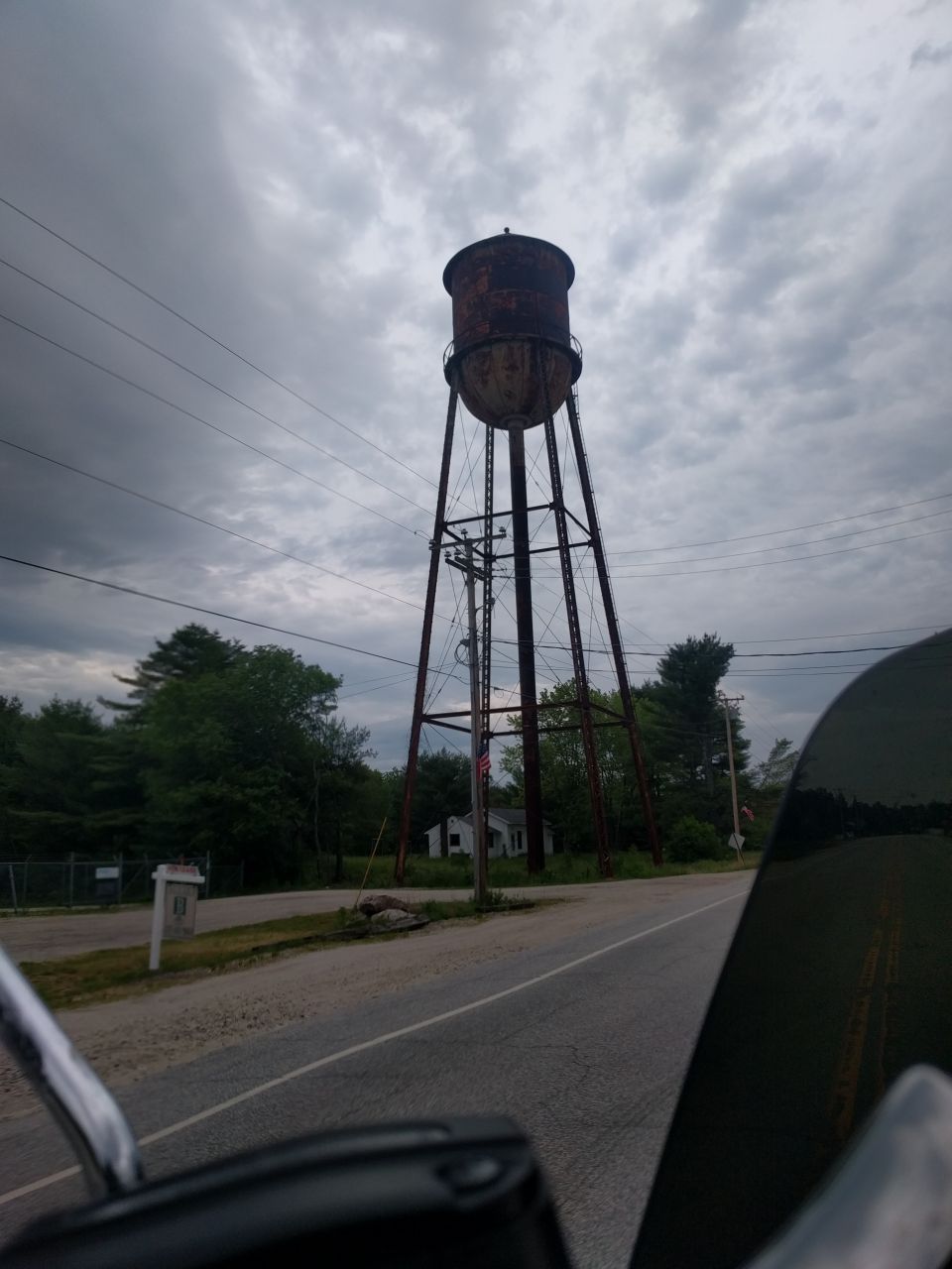 A tall, rusted water tower against a cloudy sky.