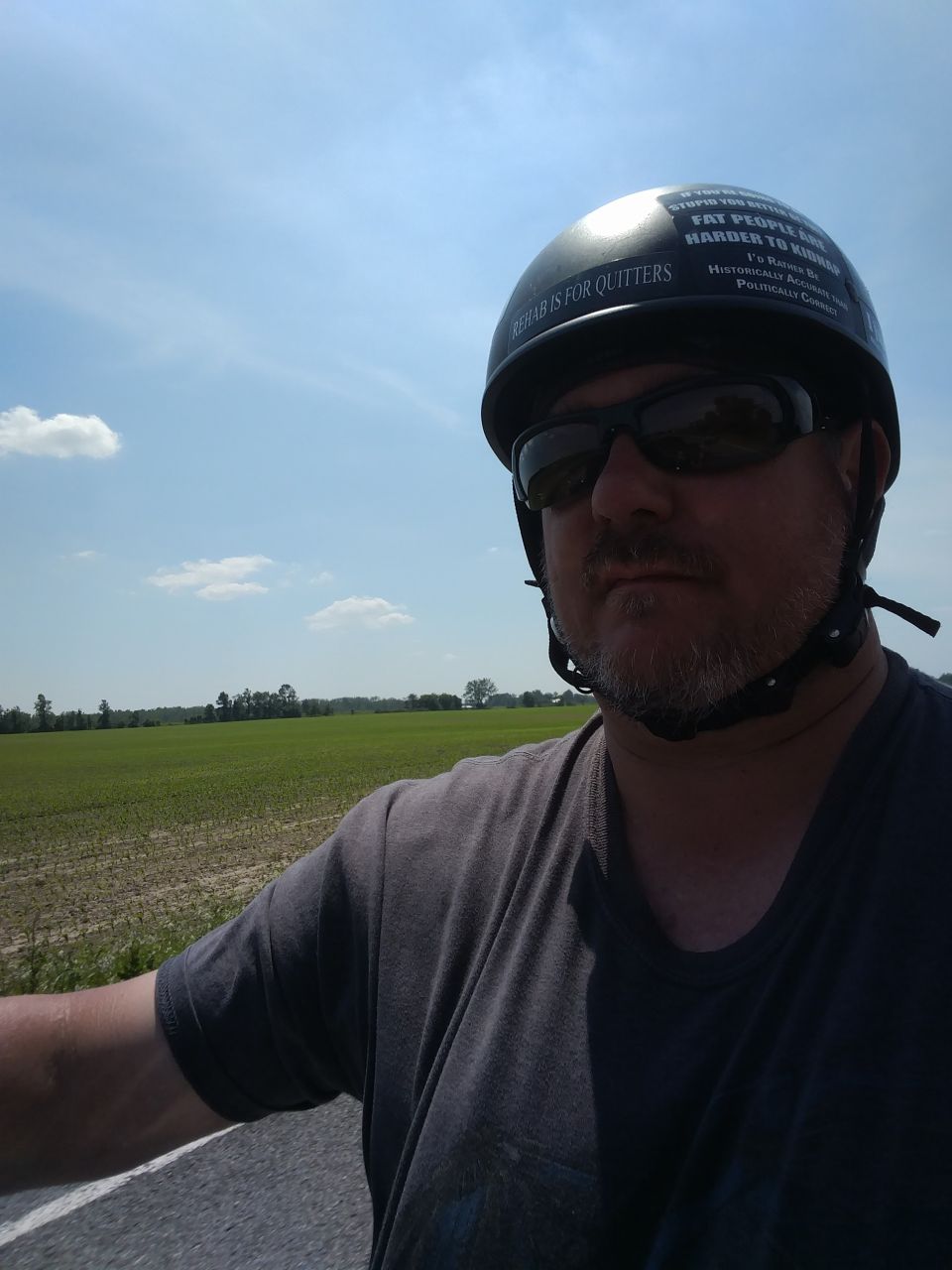 Man wearing sunglasses and a helmet with text stickers.