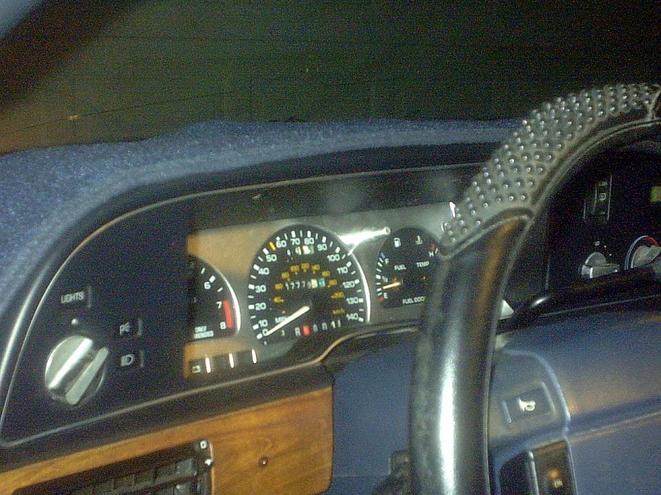 Car instrument cluster with speedometer, gauges, blue dash and studded steering wheel cover
