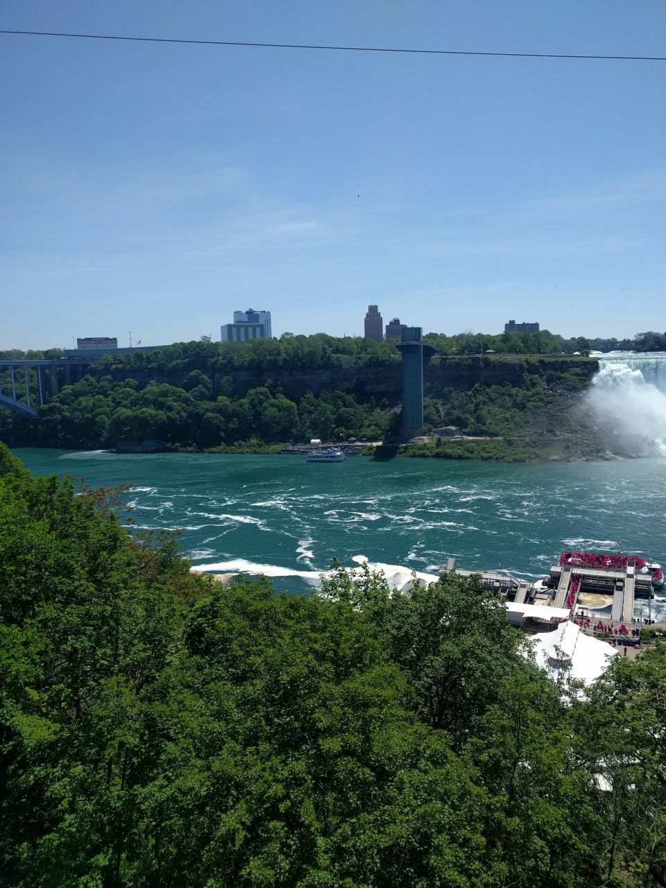 View of Niagara Falls with tour boats and trees.