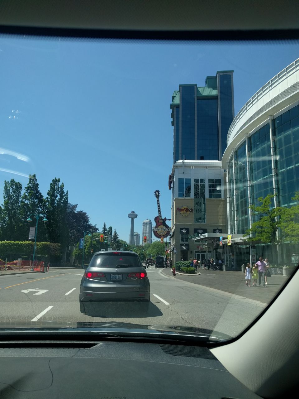 View from inside a car looking at a street with an SUV, buildings, and a Hard Rock Cafe.