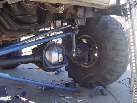 1991 Ford Bronco - Modified vehicle undercarriage with large tires and suspension work in progress.