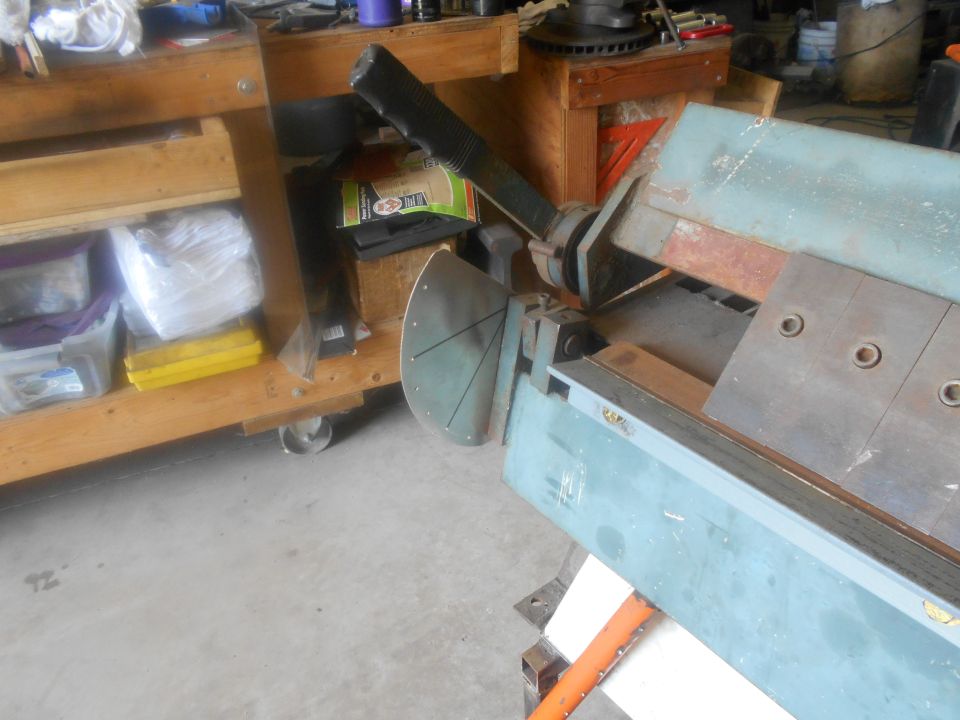 Metal shear machine on a workbench with tools and containers.