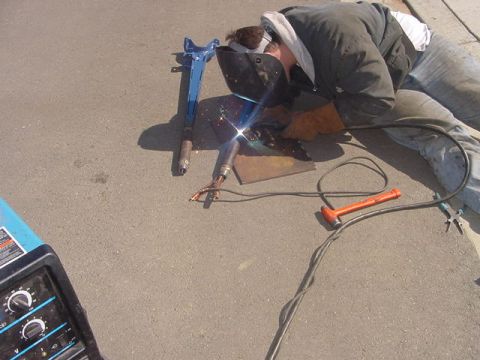 1991 Ford Bronco - Welding metal parts outdoors with a welding machine and tools nearby.