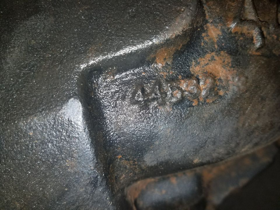 Embossed numbers 4455 on a rusty cast iron vehicle part.