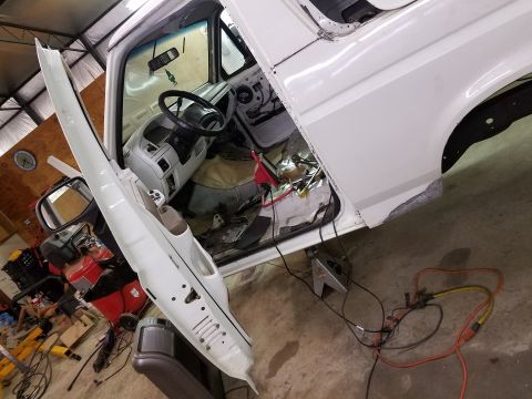 1996 Ford Bronco - The interior and driver's side of a white Ford Bronco is shown with the door open, revealing the dashboard and steering wheel. The vehicle…