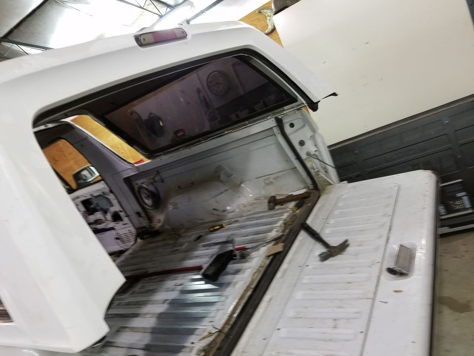 Interior of a white pickup truck bed and cab with tools.