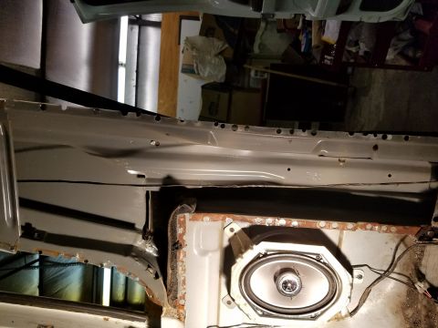 1996 Ford Bronco - The interior of a vehicle shows a speaker installed in the lower door panel area, with visible rust on the surrounding metal.
