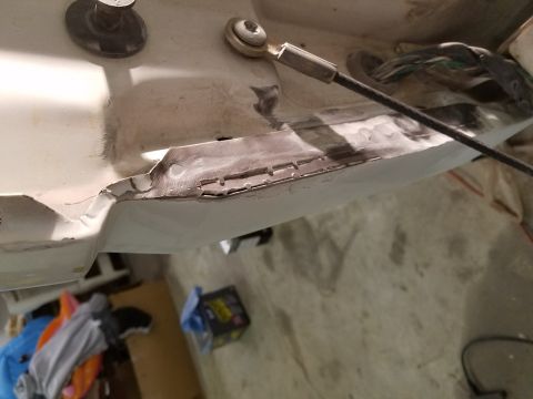 1996 Ford Bronco - A close-up view of a vehicle's body panel undergoing repair, showing primer and some damaged areas. A cable and wiring are visible in the b…