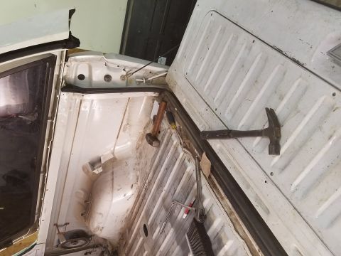 1996 Ford Bronco - A close-up view of the interior of a white vehicle, possibly a truck bed or cargo area, showing a rubber seal, a hammer, and a brush. The v…