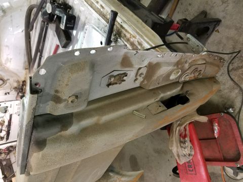 1996 Ford Bronco - A close-up view of a heavily rusted and modified car door or fender panel, showing numerous drilled holes and some bolted hardware. The pan…