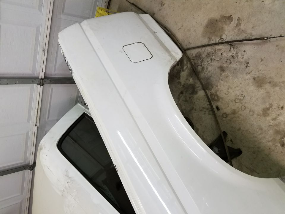 White Ford Bronco fender and door leaning against garage wall