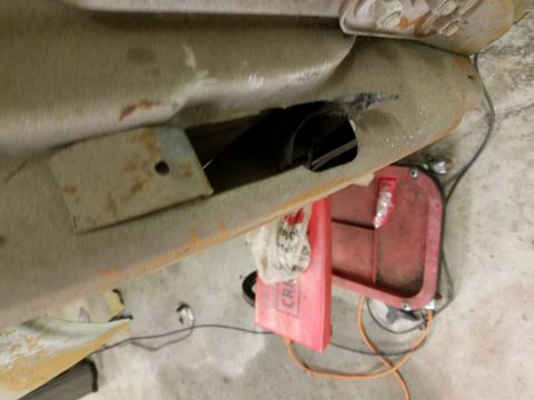 1996 Ford Bronco - A close-up view of a rusted metal part of a vehicle, possibly a frame or body panel, with a rectangular cutout. A red tool case and some wi…