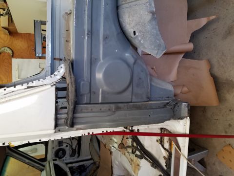1996 Ford Bronco - The image shows the interior of a vehicle undergoing restoration, focusing on the lower body panels and door jamb area. Various metal parts…