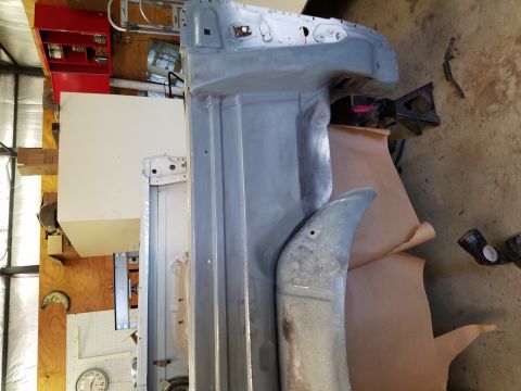 1996 Ford Bronco - A partially restored vehicle body, possibly a truck or SUV, is shown in a workshop setting. The body is painted gray primer and rests on ja…