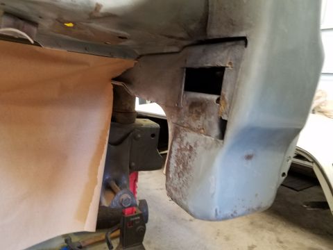 1996 Ford Bronco - The underside of a vehicle's body is shown, with a jack stand supporting a suspension component. Brown paper is used to mask off an area of…