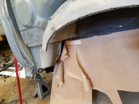 1996 Ford Bronco - The underside of a vehicle's fender well is shown, with brown paper taped to protect the area below. The vehicle is supported by a jack sta…