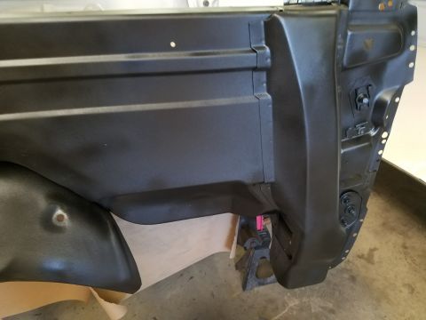 1996 Ford Bronco - This image shows a section of a vehicle's body, likely a rear quarter panel or fender well, in black paint.