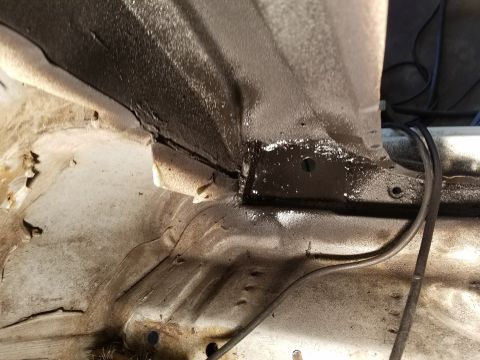 1996 Ford Bronco - Close-up view of the undercarriage of a vehicle, revealing areas of rust and protective coating.
