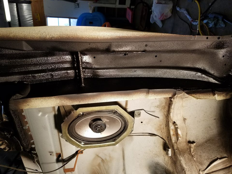 Speaker mounted in car interior panel, showing wiring and surrounding metal structure