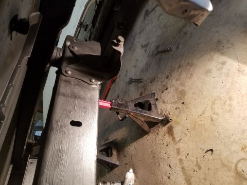 1996 Ford Bronco - A close-up view shows a vehicle's frame supported by jack stands, with various tools scattered on the concrete floor.
