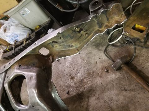 1996 Ford Bronco - A metal frame part, possibly from a vehicle, lies on a workshop floor next to a hammer.