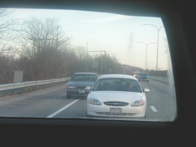 1997 Ford Taurus - A white Ford Taurus drives on a highway, with another car in front of it.