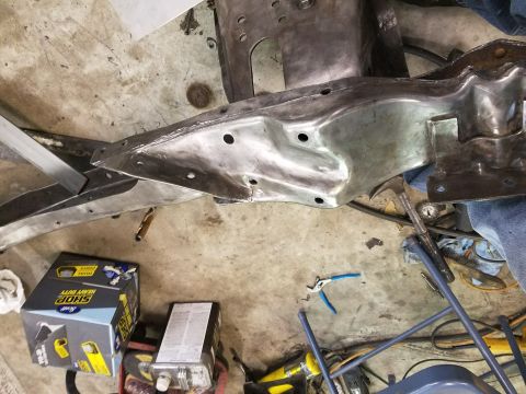 1996 Ford Bronco - Metal vehicle frame part with bolt holes and welds, on a workshop floor.