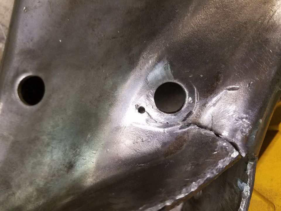 Close-up of a damaged metal bracket with two holes and a visible crack