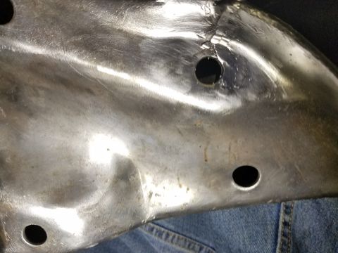 1996 Ford Bronco - Close-up of a dented metal panel with visible holes, resting on denim fabric.