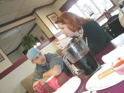 1997 Ford Taurus - Two people sit at a table in a restaurant, with a large pitcher of dark liquid and cups.