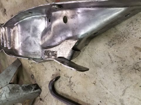 1996 Ford Bronco - A close-up view of a damaged metal part, possibly from a vehicle, lying on a concrete surface.