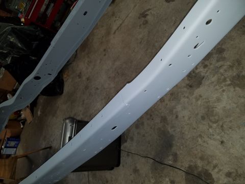 1996 Ford Bronco - Painted vehicle frame rails sit on a concrete floor, possibly awaiting reassembly.