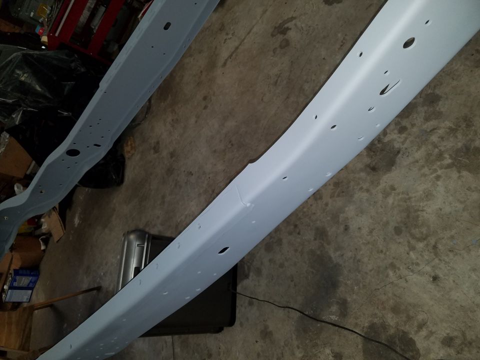 Two painted vehicle frame rails on a concrete floor