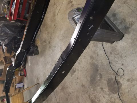 1996 Ford Bronco - A black painted vehicle frame is shown in a workshop setting.
