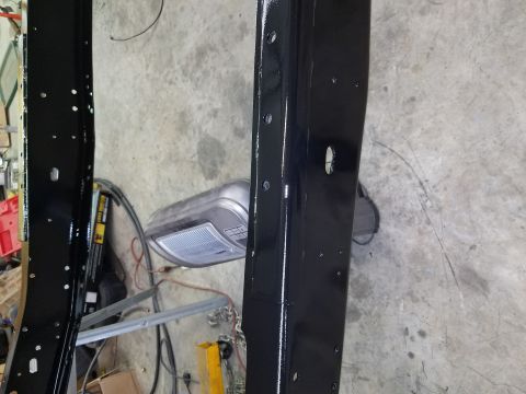 1996 Ford Bronco - Close-up view of black painted frame rails, likely from a truck or SUV, showing mounting holes and a section of a garage door opener in the…